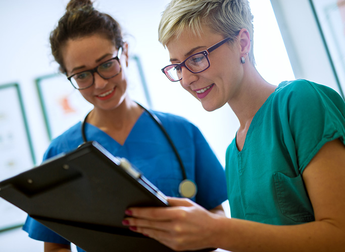 Close up view of two professional nurses with eyeglasses checking the patient papers in a doctors office.