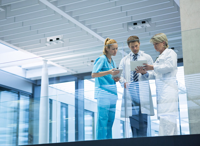 Medical team discussing over digital tablet in corridor