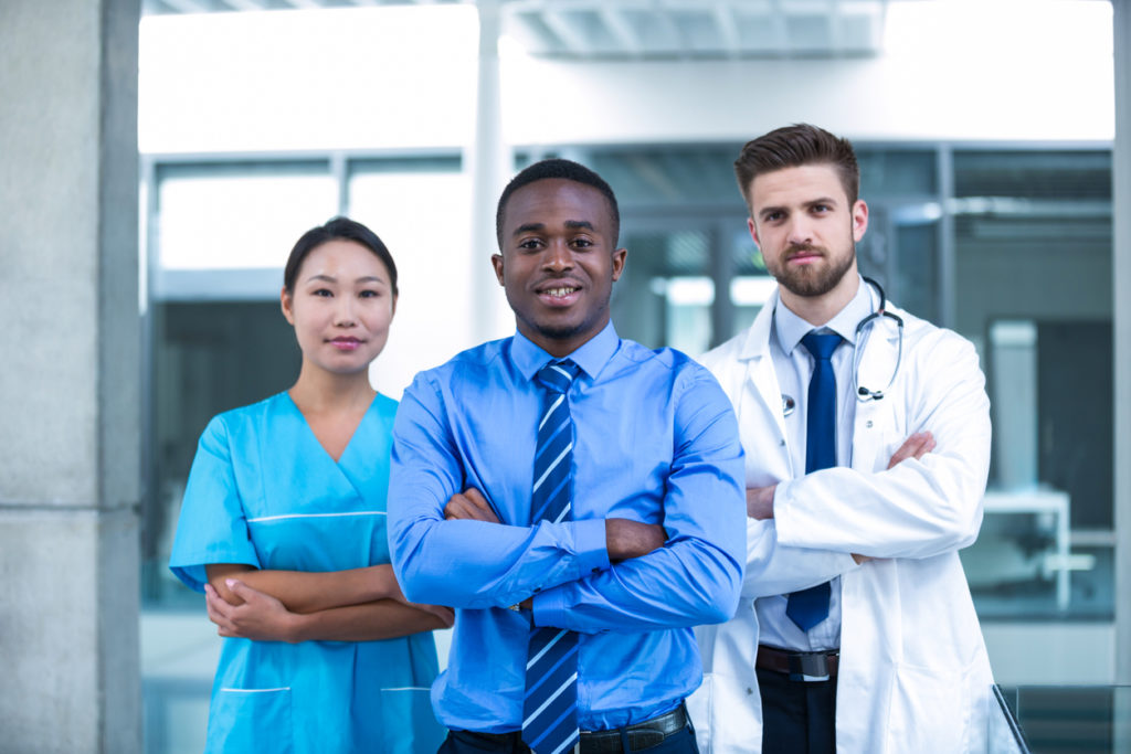 Nurse and doctor with businessman standing in hospital